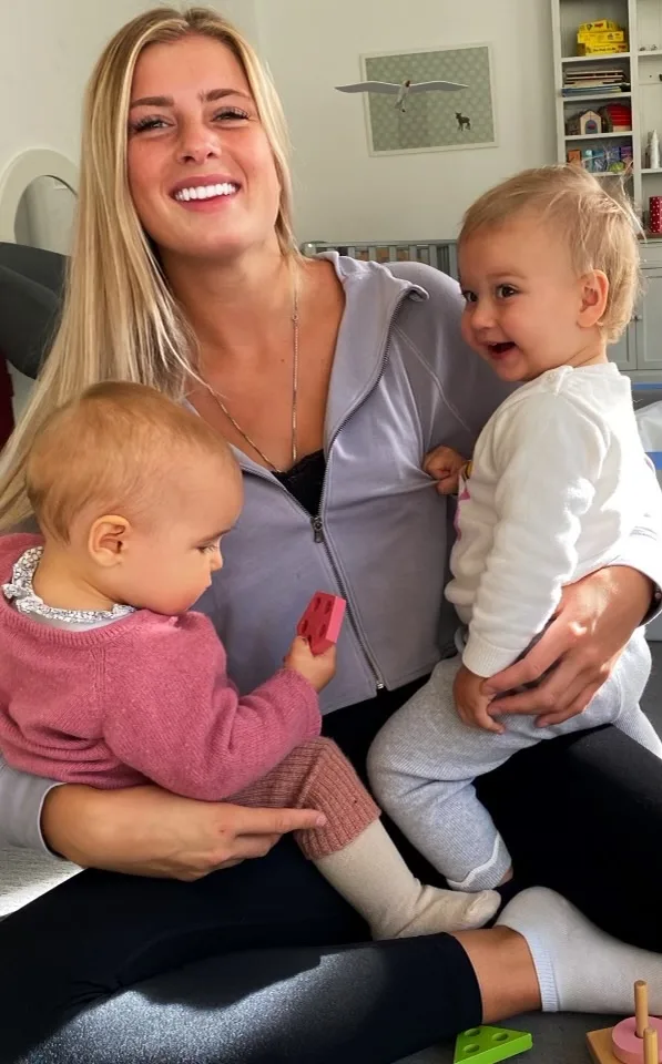 Betreuerin lacht mit zwei Kleinkindern auf dem Arm